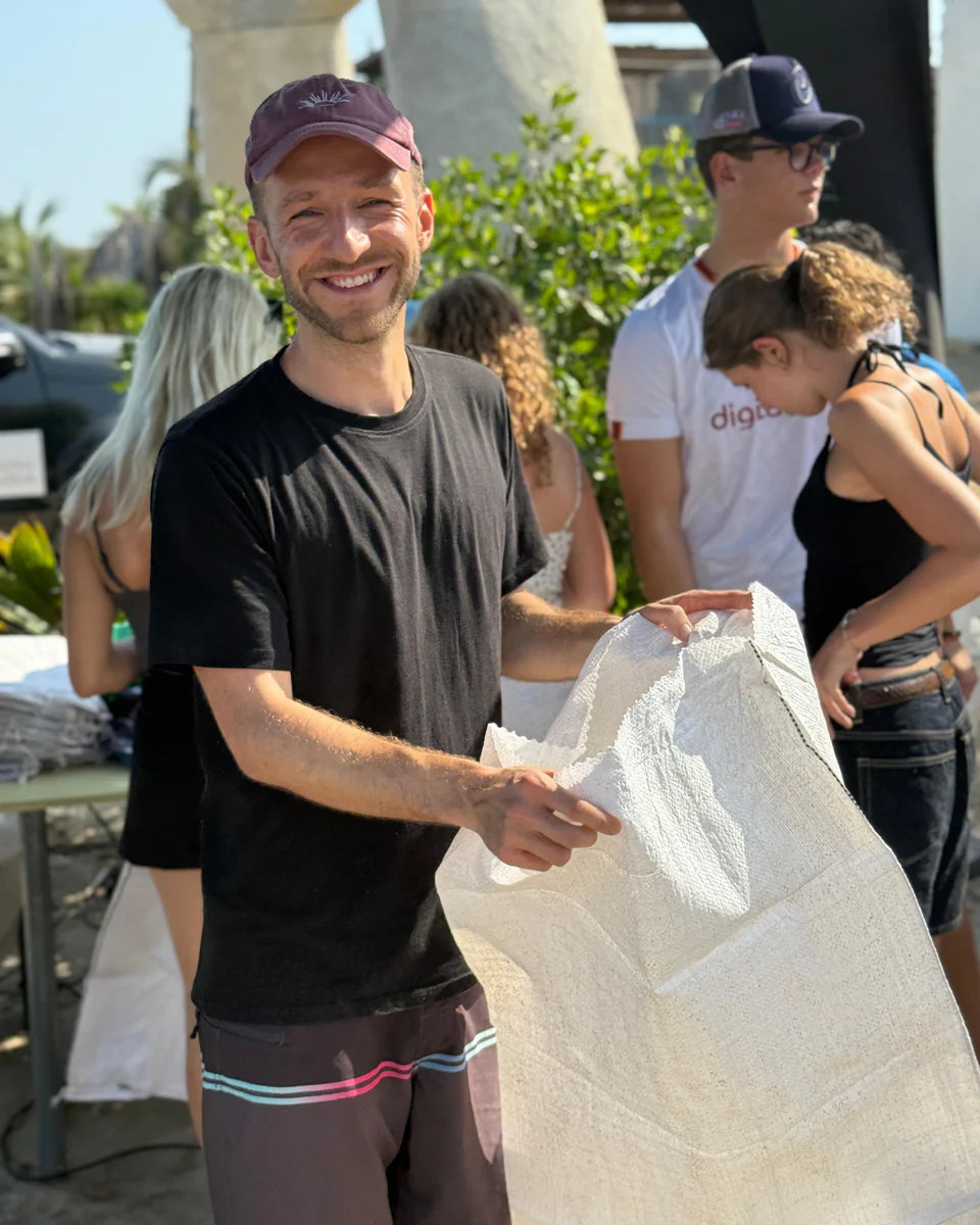 Fynn Hedrich, founder of OceanPulse, holding a collection bag on the beach