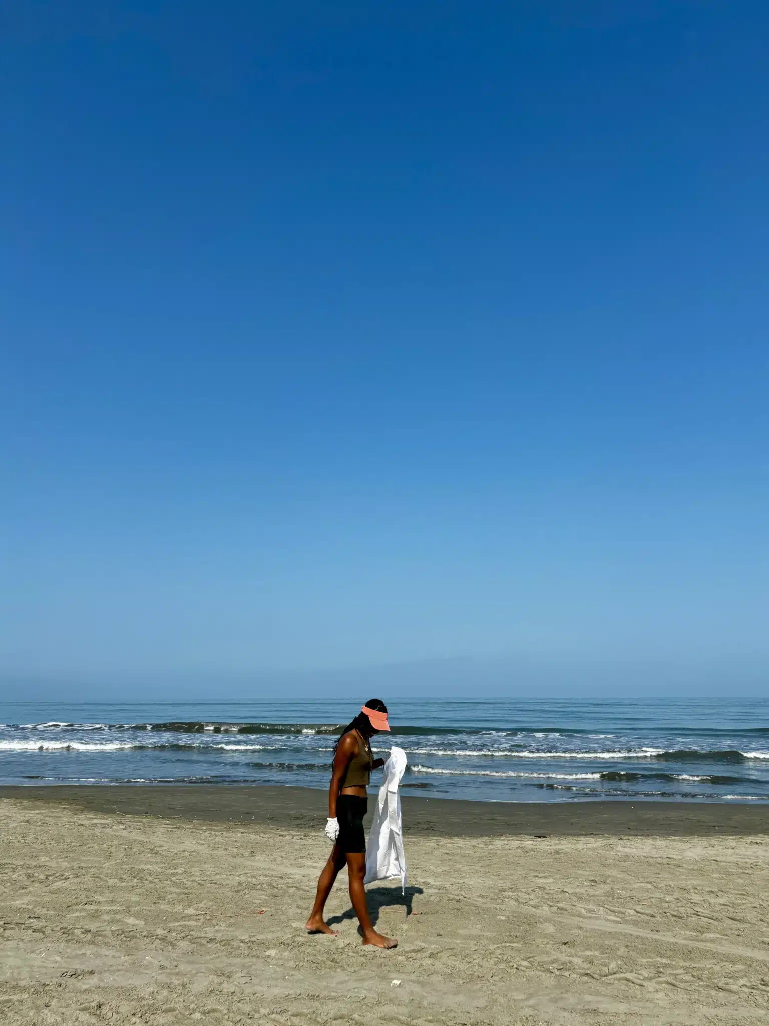 Frau spaziert am Strand von La Boquilla, Kolumbien, bei blauem Himmel