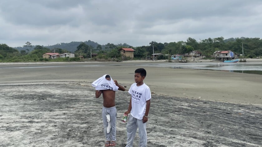 Zwei Jungen am Strand von Mompiche tragen weiße Ocean Pulse T-Shirts nach einer Umweltaktion.