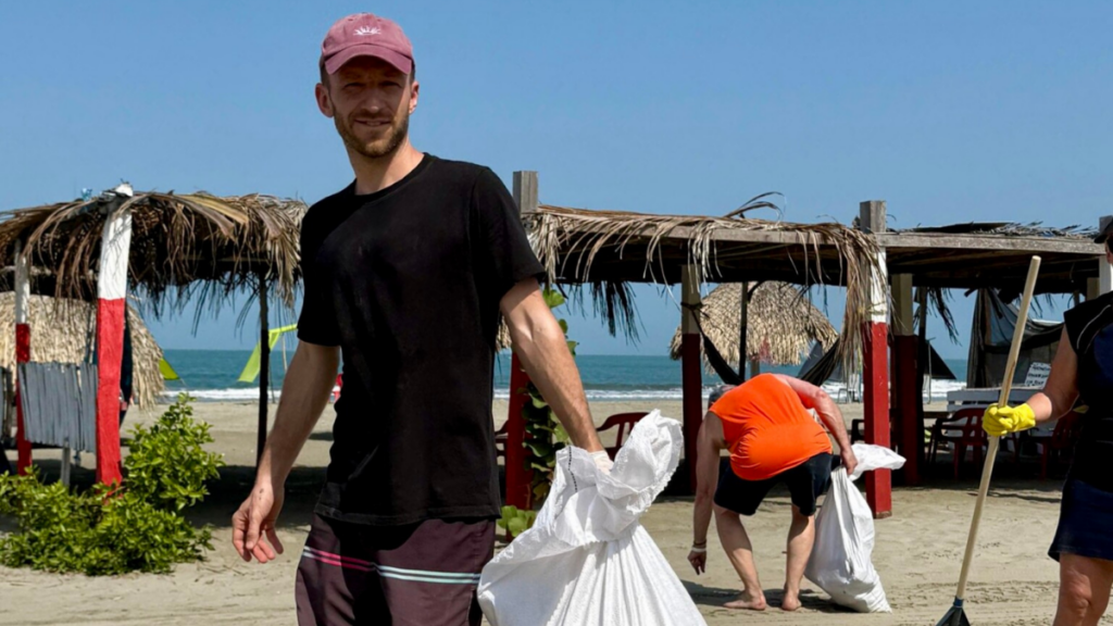 Volunteer removing heavy plastic waste from the beach during an OceanPulse marine conservation mission.